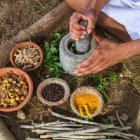 A young man preparing ayurvedic medicine in the traditional manner.